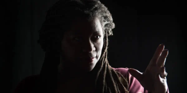 Storyteller Donna Washington, lit from the side, looking engagingly towards the viewer. On page for her performance.