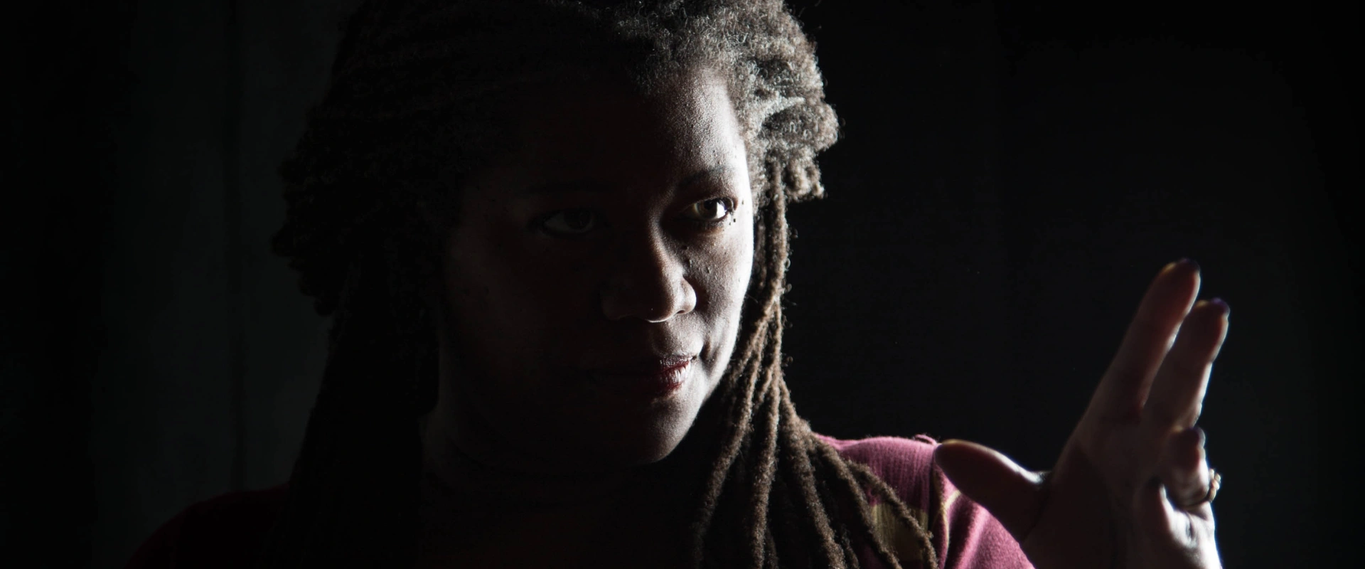 Storyteller Donna Washington, lit from the side, looking engagingly towards the viewer. On page for her performance.