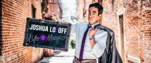 Magician Josh Lozoff holding a sign for his "Life is Magic" show in an alleyway.