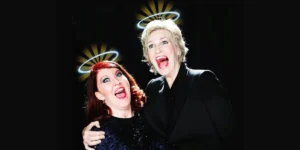 Jane Lynch and Kate Flannery with halos, mouths open in a comedic expression. For "The Trouble with Angels" event.