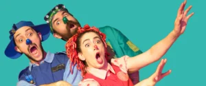 Three performers in colorful, whimsical costumes and clown noses with exaggerated, surprised expressions. On page for Yellow Bird Chase.