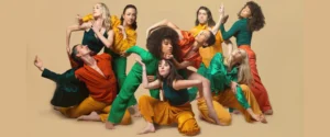 Company of Stewart/Owen Dancers posed for a photo, all wearing bright colored costumes.