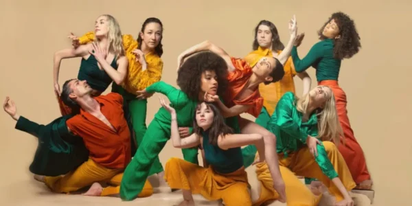 Company of Stewart/Owen Dancers posed for a photo, all wearing bright colored costumes.