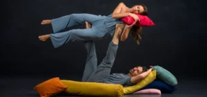 Photo: dancers Gavin Stewart and Vanessa Owens. Gavin laying with back to the ground propping Vanessa in the air; Vanessa posed with a pillow and acting if she were asleep.