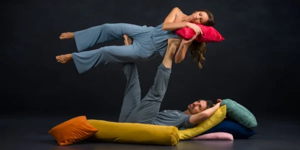 Photo: dancers Gavin Stewart and Vanessa Owens. Gavin laying with back to the ground propping Vanessa in the air; Vanessa posed with a pillow and acting if she were asleep.