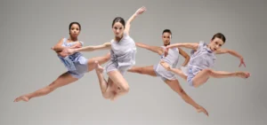 Photo: four female dancers posed jumping in mid-air