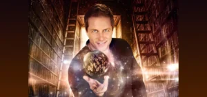 Photo: Mike Super smiling posed with a floating crystal ball; applauding people can be seen inside the crystal ball
